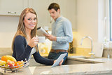 Woman drinking hot beverage using tablet pc in kitchen