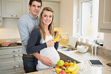 Man embracing pregnant wife holding a banana