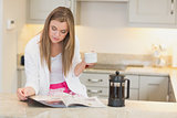 Woman drinking coffee while reading the newspaper