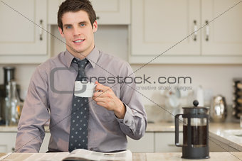 Man drinking coffee while reading newspaper