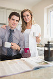 Couple drinking coffee together while reading newspaper