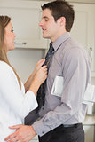 Woman talking with her husband and fixing tie