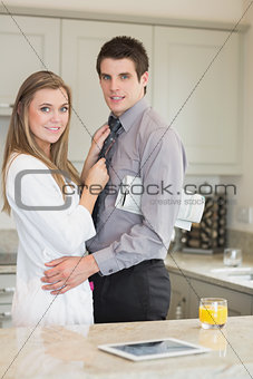Woman hugging her husband with a newspaper under his arm
