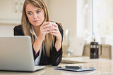 Concentrated woman looking at laptop with coffee in hand