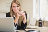 Happy woman holding hot beverage with laptop