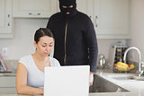 Woman typing on the laptop while  burglar looking at it