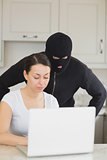 Burglar looking at the laptop behind  woman