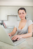 Woman typing on laptop in the kitchen