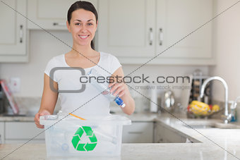 Woman throwing bottle into recycling bin