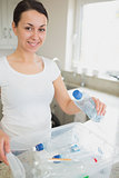 Woman throwing many bottles into recycling bin