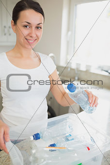 Woman throwing many bottles into recycling bin