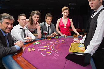 People sitting at the blackjack table smiling at the casino