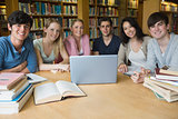 Six students learning in a library with a laptop