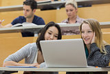 Students in a lecture hall with a laptop