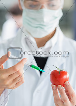 Woman injecting a tomato