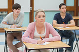 Three students in a classroom about to take notes