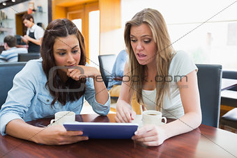 Students watching something shocking on tablet in canteen