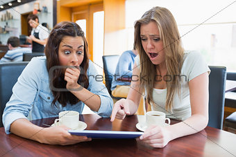 Women holding a tablet and looking surprised