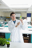 Student holding up beaker with seedling in it
