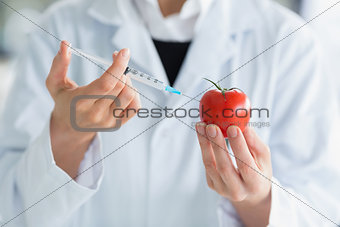 Woman injecting liquid in tomato