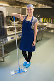 Smiling woman cleaning the kitchen floor