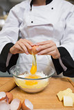 Chef breaking eggs into flour