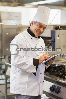 Smiling chef using digital tablet
