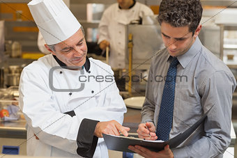 Head chef and waiter discussing menu