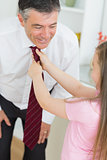 Father leaning down to let daughter fix tie