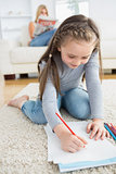 Little girl drawing sitting on floor with mother reading newspaper