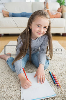 Happy girl drawing with her mother reading newspaper