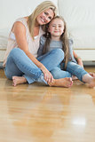 Mother and daughter sitting on the floor embracing