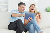 Husband and wife laughing at tablet pc