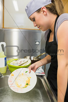 Unsmiling woman washing a plate