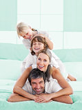 Smiling family piled on top of dad