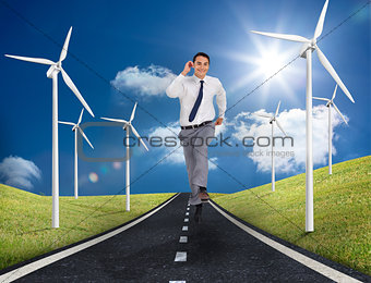Businessman running on a road next to windmills
