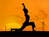 Silhouette of woman doing yoga with wind turbines