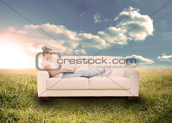 Woman using laptop on couch in field
