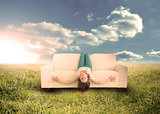 Woman sitting upside down on couch in field