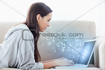 Woman using laptop with binary codes floating over