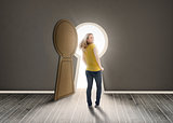 Woman walking towards keyhole shaped doorway with light