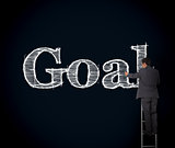 Businessman writing goal on a giant blackboard