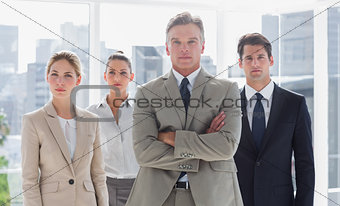Boss with his arms folded standing with serious colleagues behind