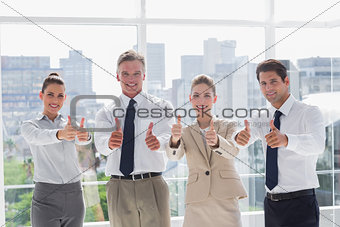Smiling team of business people giving thumbs up