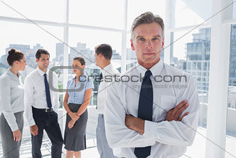 Boss with arms folded standing in a modern office