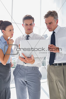 Three business people using a laptop