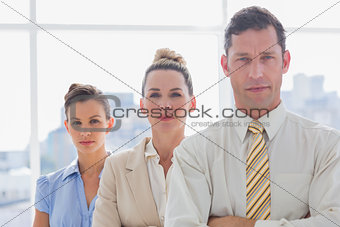 Serious handsome businessman standing with arms folded