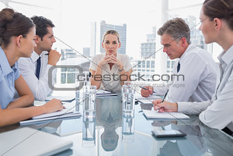 Serious businesswoman looking at camera with colleagues around