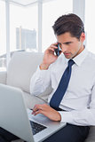 Businessman calling with his cell phone and using his laptop