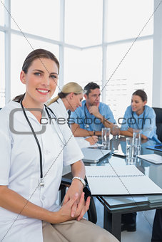 Attractive doctor sitting in front of her team